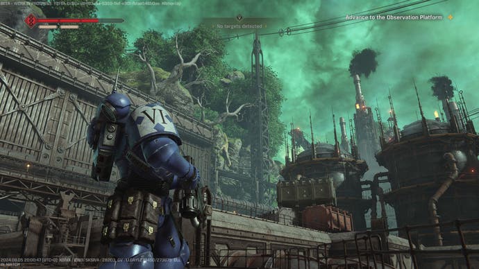 A custom Space Marine looks up at a large refinery in Operations mode in Warhammer 40K: Space Marine 2.